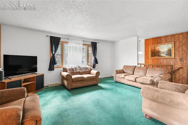 living room with carpet, wooden walls, visible vents, and a textured ceiling