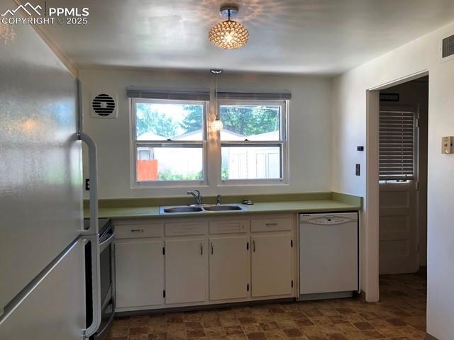 kitchen with freestanding refrigerator, white cabinetry, white dishwasher, a sink, and range with electric cooktop