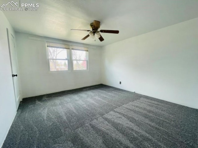 empty room featuring a ceiling fan and dark carpet