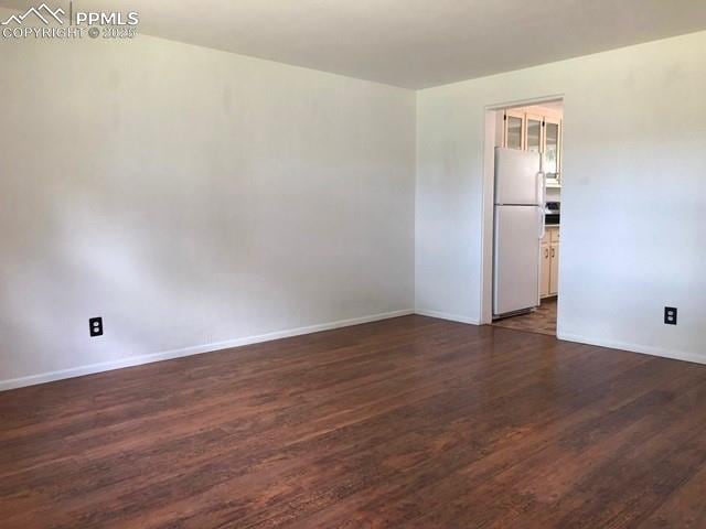 spare room featuring dark wood finished floors and baseboards