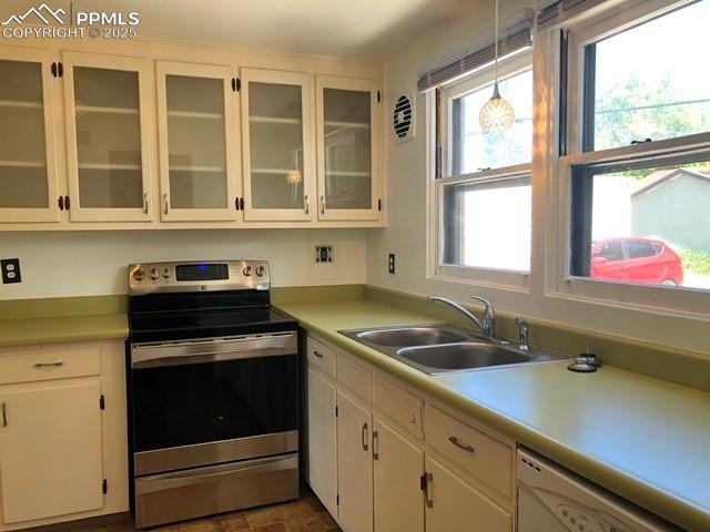 kitchen with light countertops, hanging light fixtures, stainless steel range with electric cooktop, white dishwasher, and a sink