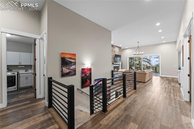 hall featuring recessed lighting, dark wood-type flooring, an upstairs landing, a chandelier, and baseboards