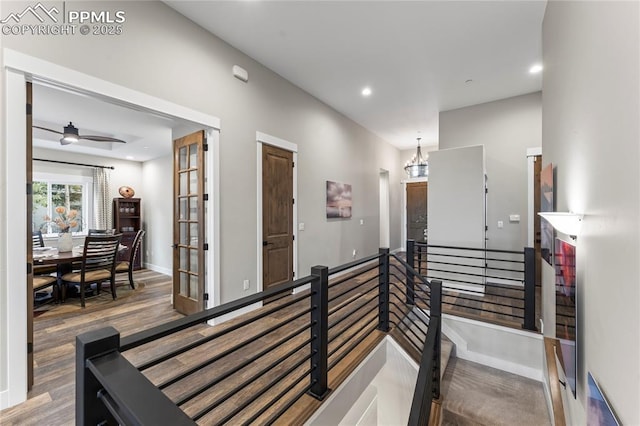 hall featuring recessed lighting, a chandelier, wood finished floors, and an upstairs landing