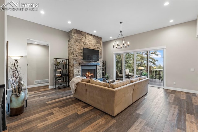 living area featuring a stone fireplace, dark wood finished floors, visible vents, and baseboards