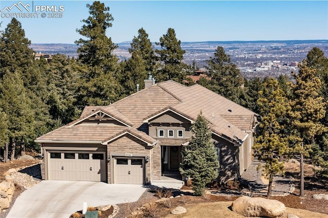 view of front of home featuring a garage, concrete driveway, a chimney, and a tile roof