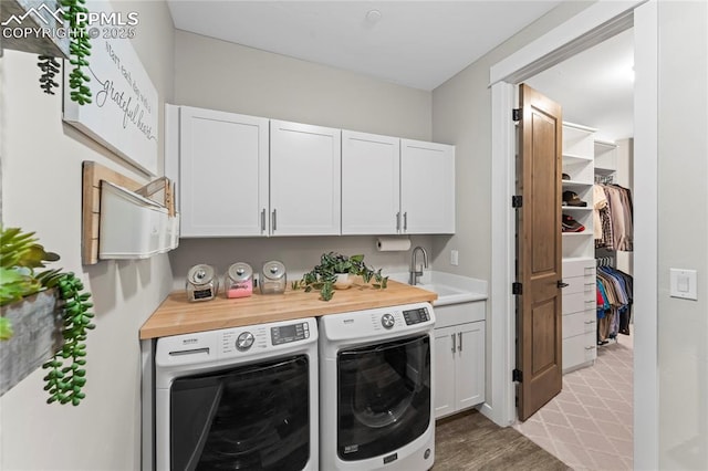 laundry area featuring washing machine and dryer, cabinet space, and a sink