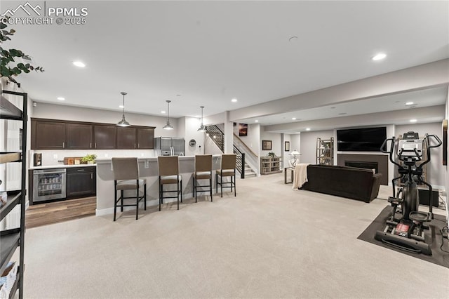 interior space with stainless steel fridge with ice dispenser, wine cooler, open floor plan, dark brown cabinets, and a kitchen bar