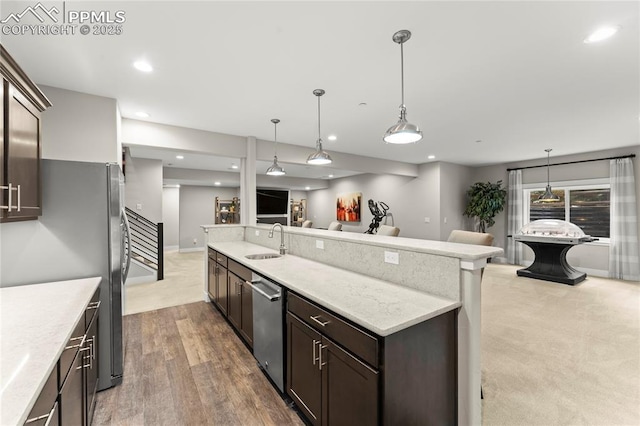 kitchen featuring appliances with stainless steel finishes, open floor plan, dark brown cabinets, a sink, and recessed lighting