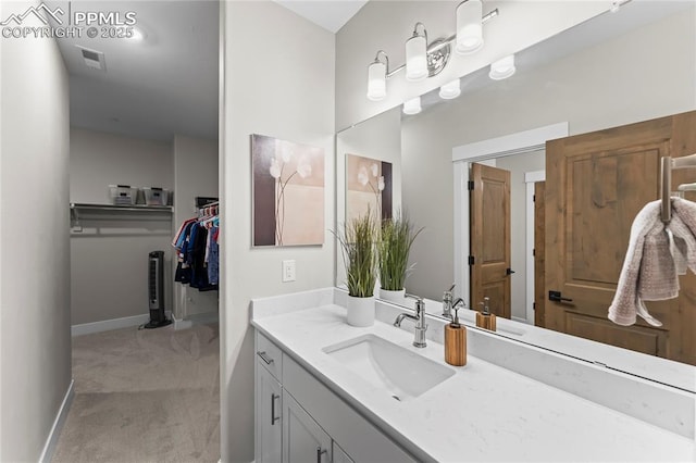 bathroom featuring visible vents, a walk in closet, vanity, and baseboards