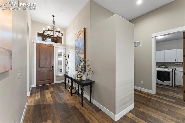 entrance foyer featuring a notable chandelier, visible vents, baseboards, dark wood finished floors, and washer / dryer