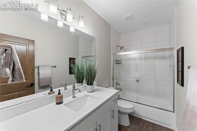 full bathroom with visible vents, toilet, combined bath / shower with glass door, vanity, and wood finished floors