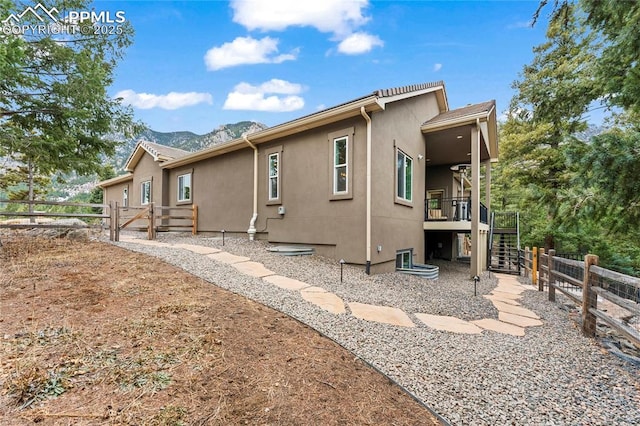 view of side of home featuring stairs, fence, and stucco siding