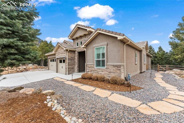 view of front facade featuring stucco siding, fence, a garage, stone siding, and driveway