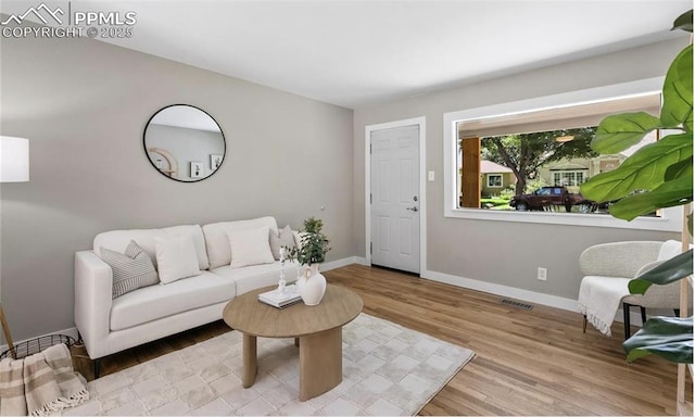 living room featuring light wood-type flooring, baseboards, and visible vents