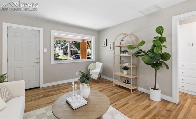 sitting room featuring light wood-type flooring, visible vents, and baseboards