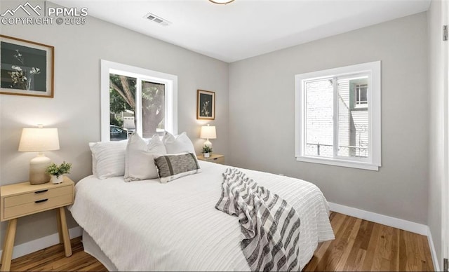 bedroom featuring baseboards, visible vents, and wood finished floors