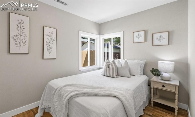 bedroom featuring wood finished floors, visible vents, and baseboards