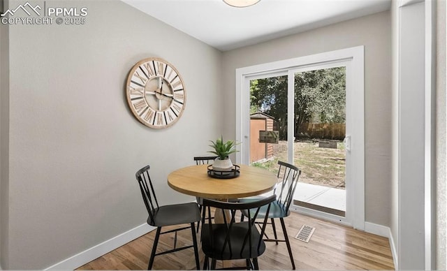 dining area with light wood-style flooring, visible vents, and baseboards