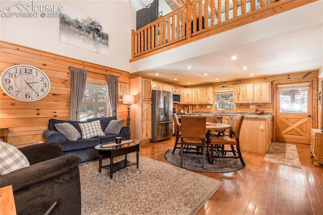 living room featuring recessed lighting, light wood-type flooring, a high ceiling, and wooden walls