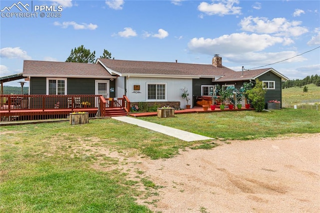 view of front of house featuring a front yard, a chimney, and a wooden deck