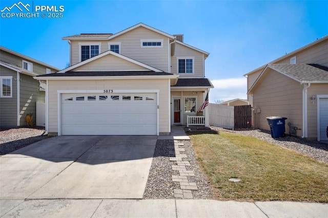 traditional-style house with a garage, concrete driveway, fence, and a front lawn