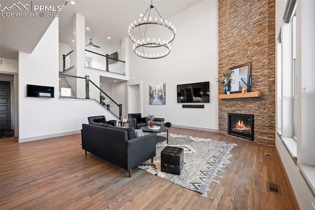 living room with ceiling fan, a fireplace, wood finished floors, visible vents, and stairs