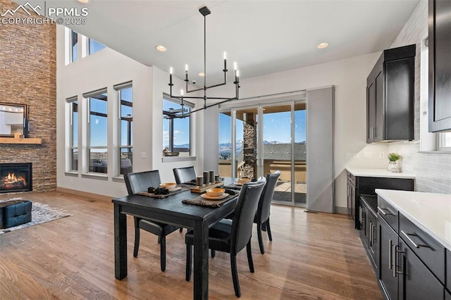 dining space with a stone fireplace, recessed lighting, wood finished floors, and baseboards