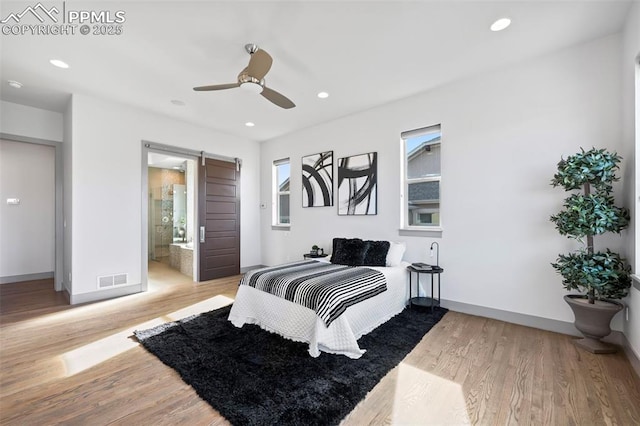 bedroom with a barn door, visible vents, wood finished floors, and recessed lighting