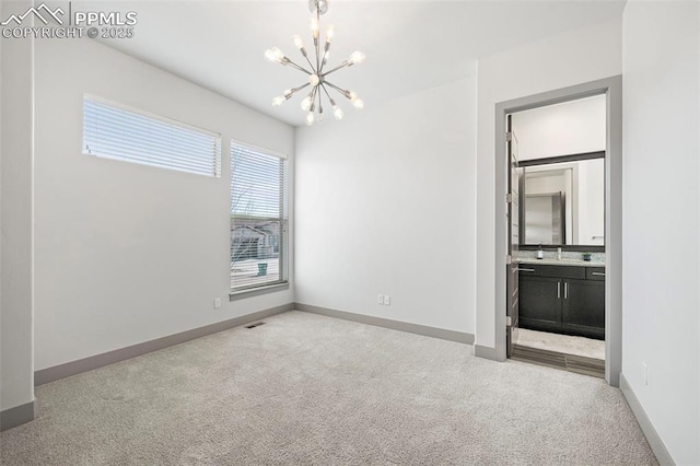 carpeted empty room with a sink, baseboards, and a notable chandelier