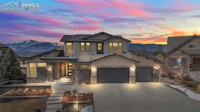 view of front of property with a mountain view, stone siding, driveway, and stucco siding