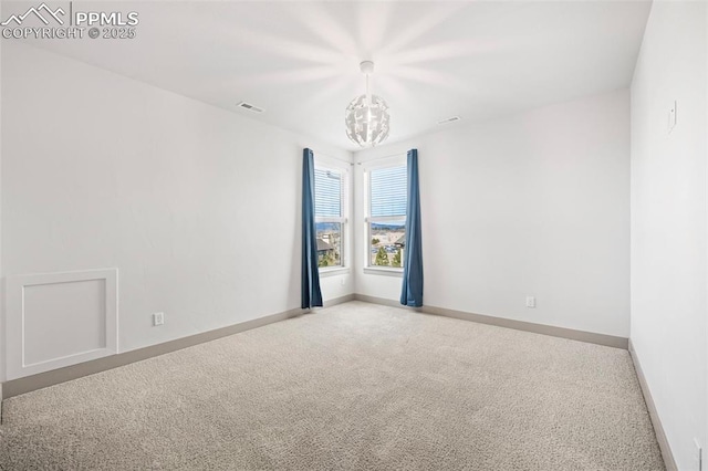 carpeted spare room featuring visible vents, a notable chandelier, and baseboards