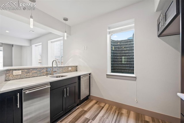 kitchen with light countertops, stainless steel dishwasher, decorative backsplash, and dark cabinets