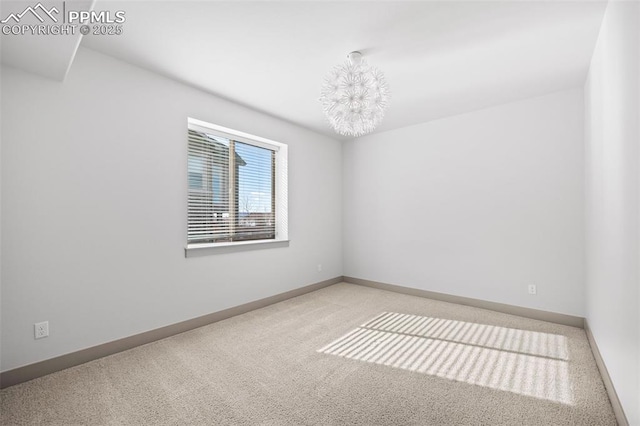 empty room featuring an inviting chandelier, baseboards, and carpet flooring