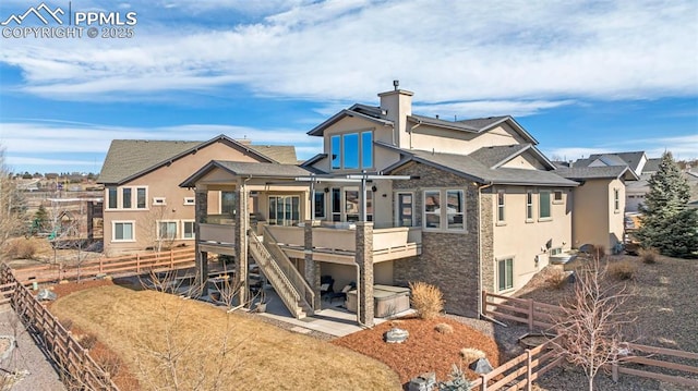 back of house with stone siding, a fenced backyard, a wooden deck, a patio area, and stucco siding