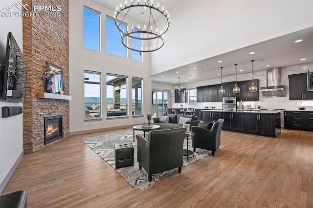 living room featuring a chandelier, recessed lighting, a fireplace, wood finished floors, and baseboards