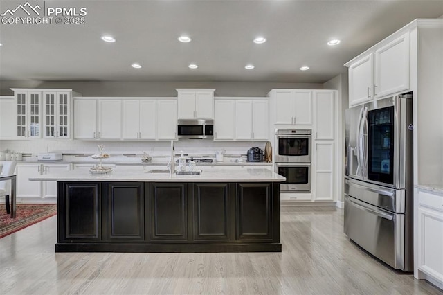 kitchen featuring a sink, white cabinetry, appliances with stainless steel finishes, decorative backsplash, and light wood finished floors