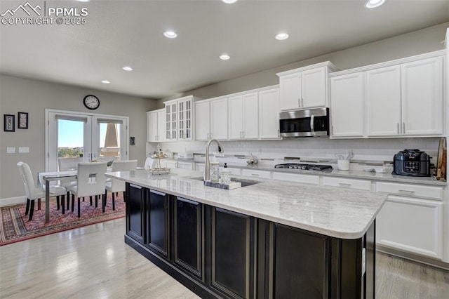 kitchen with stainless steel appliances, tasteful backsplash, a sink, and white cabinetry