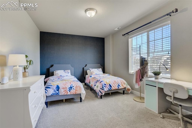 bedroom featuring baseboards, an accent wall, visible vents, and light colored carpet