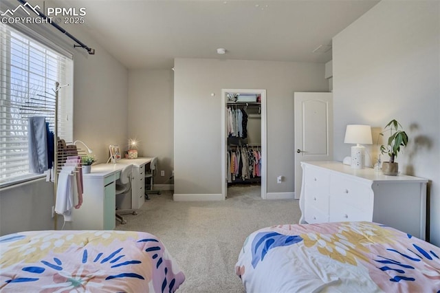 bedroom with light carpet, a closet, a walk in closet, and baseboards