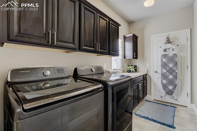 laundry room featuring cabinet space, light tile patterned flooring, a sink, separate washer and dryer, and baseboards