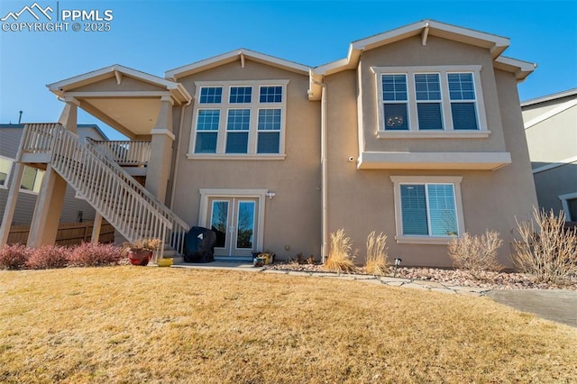 view of front of house featuring a front yard, french doors, stairway, and stucco siding