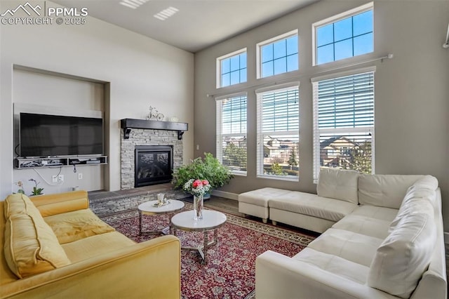 living room featuring a fireplace, baseboards, and wood finished floors