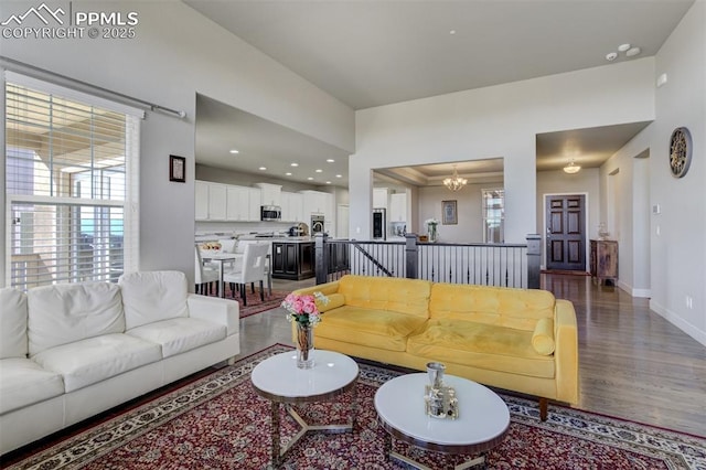 living area featuring baseboards, recessed lighting, wood finished floors, and a notable chandelier