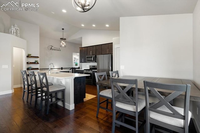 kitchen featuring stainless steel appliances, a sink, dark brown cabinets, dark wood-style floors, and a center island with sink