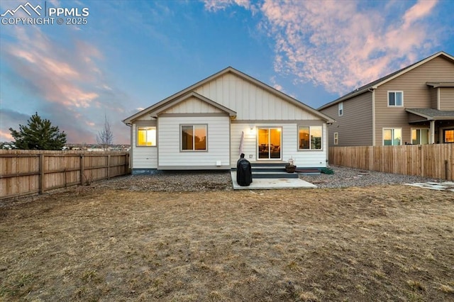 rear view of property featuring entry steps, a fenced backyard, and board and batten siding