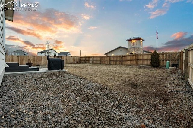 yard at dusk with a patio and a fenced backyard