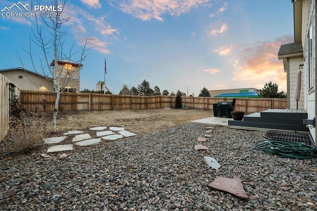 yard at dusk with a patio area and a fenced backyard