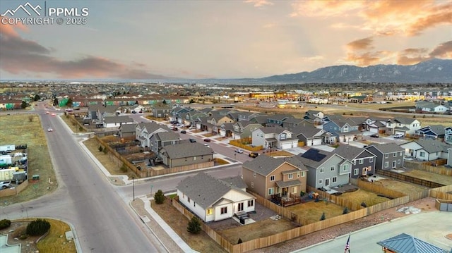 aerial view at dusk featuring a mountain view and a residential view