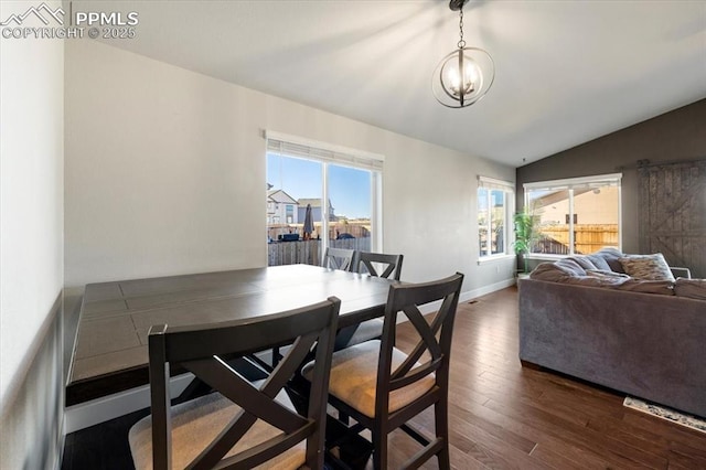 dining room with lofted ceiling, a notable chandelier, wood finished floors, and baseboards