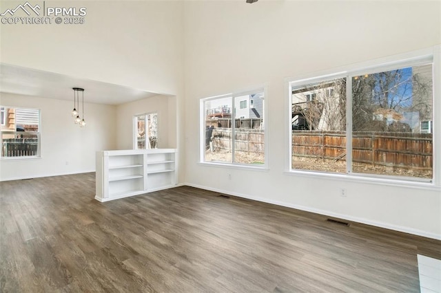 empty room with dark wood-style floors, visible vents, and baseboards